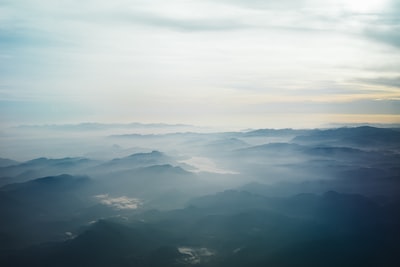 航空摄影的蓝色山被雾包围在白色的天空在白天
